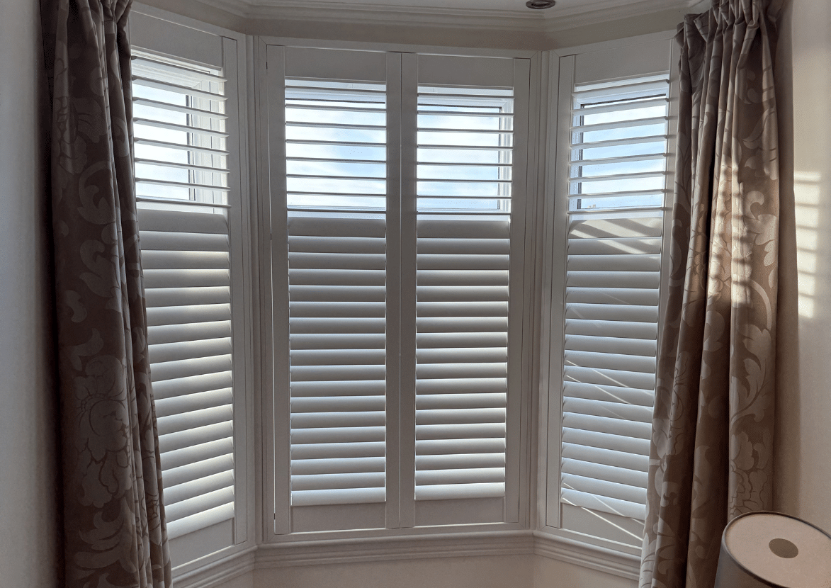 Bespoke white full-height shutters with a mid-rail installed in a traditional Glasgow bay window.