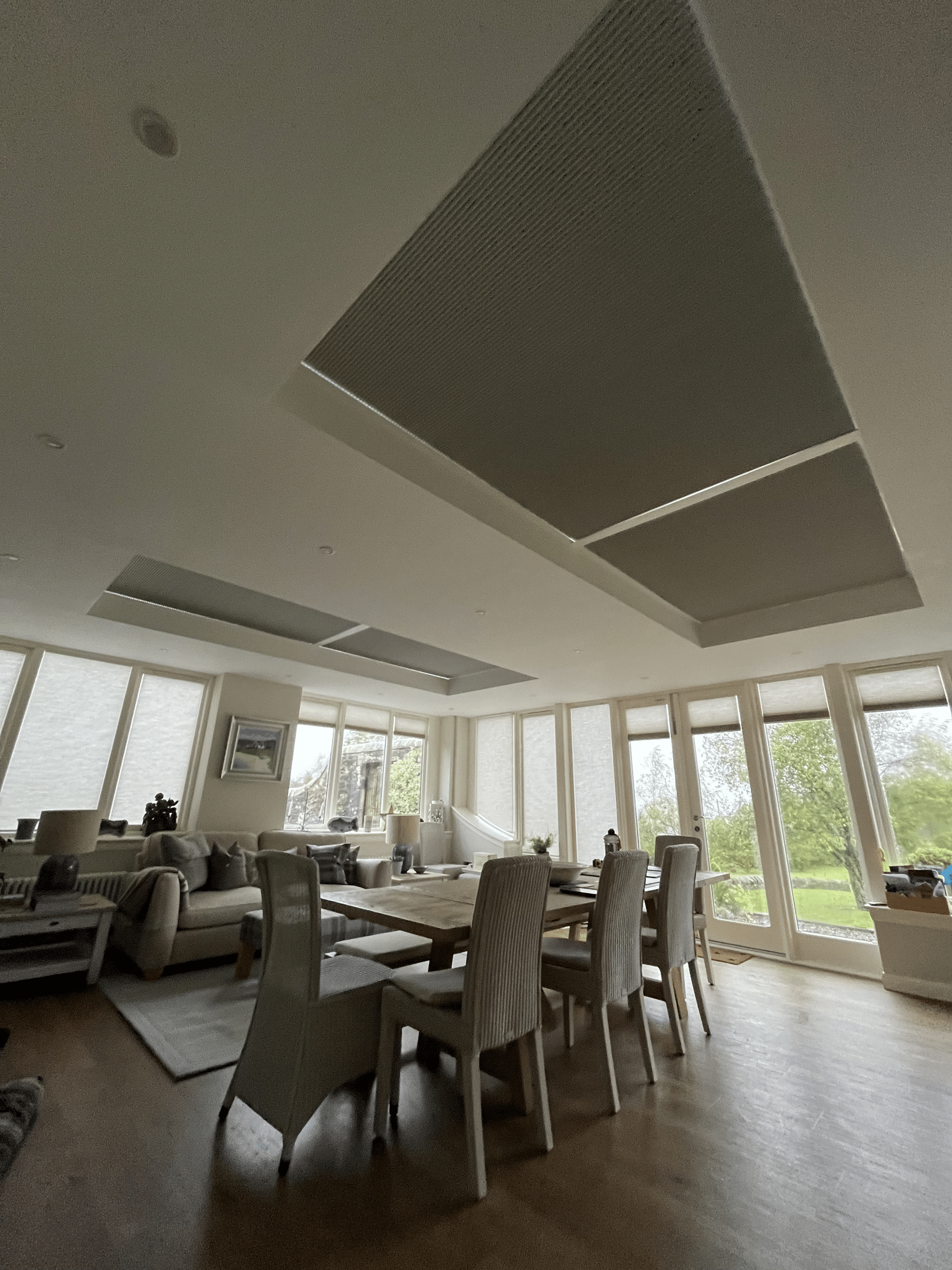 Large open-plan living space in Fife featuring fully closed grey thermal skylight blinds above a dining table.