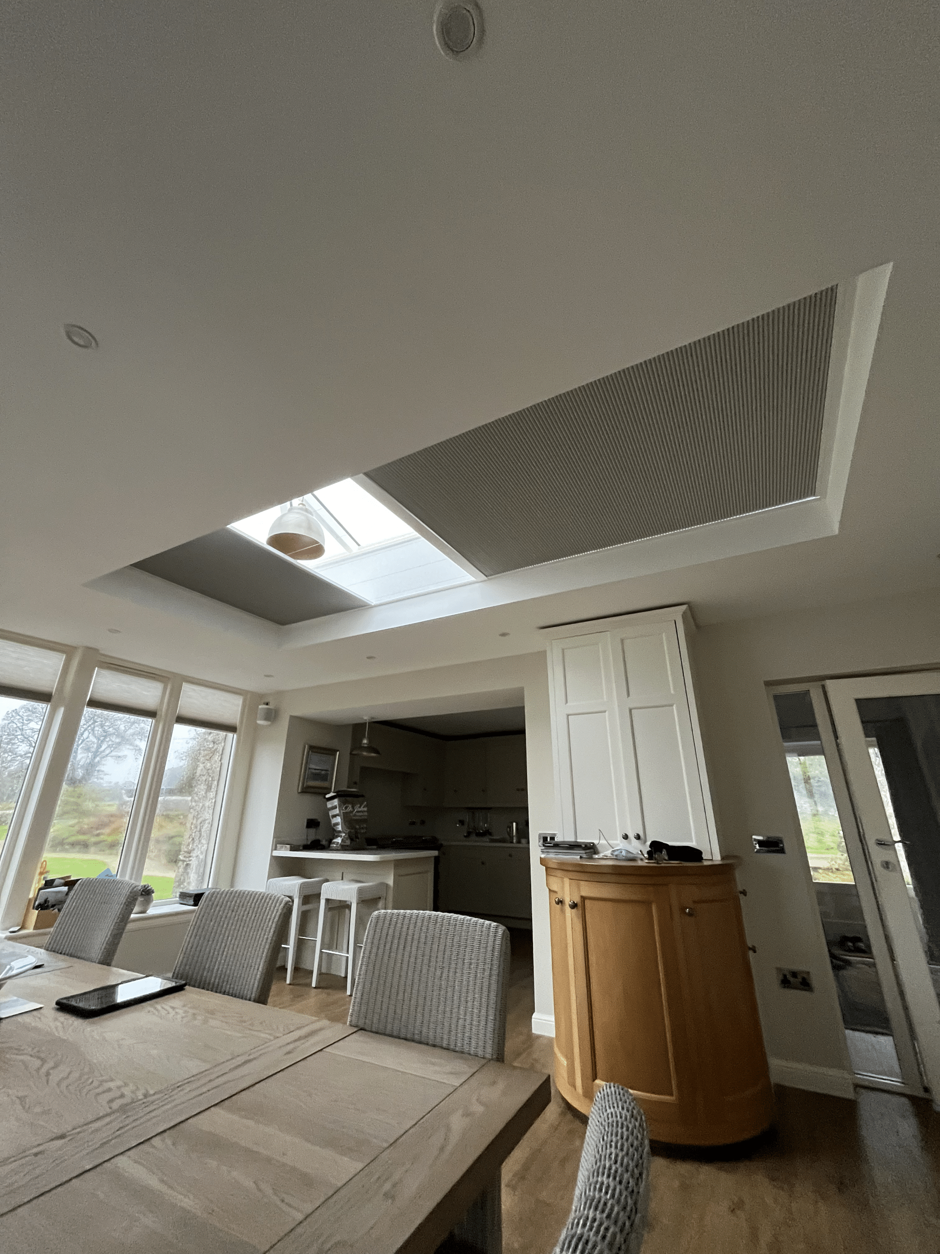Modern open-plan kitchen and dining room in Cupar featuring partially closed motorised skylight blinds.